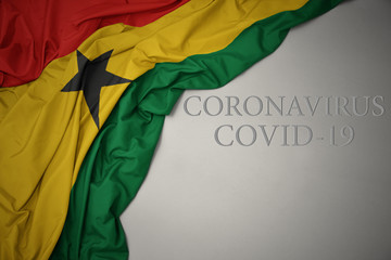 waving national flag of ghana on a gray background with text coronavirus covid-19 . concept.