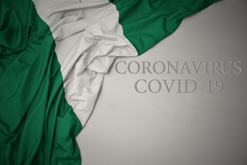 waving national flag of nigeria on a gray background with text coronavirus covid-19 . concept.