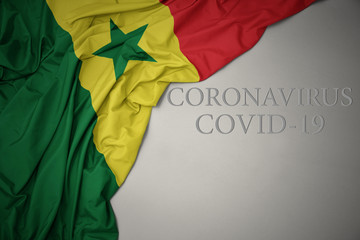 waving national flag of senegal on a gray background with text coronavirus covid-19 . concept.