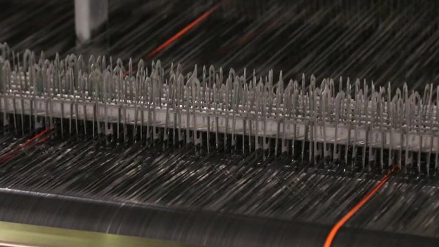 Close up of textile machine. Fibre thread lines on the weaving loom machine. A loom machine for clothing or woven clothes. Weaving machine for garment industry.