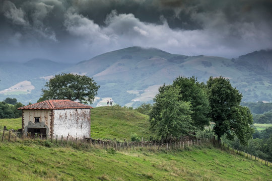 Paisaje campestre del valle de Baztan en Navarra con casa de campo, arboles y las colinas al fondo (España).