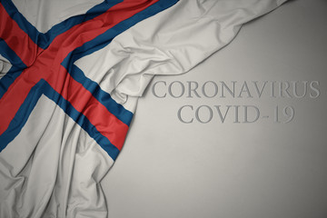 waving national flag of faroe islands on a gray background with text coronavirus covid-19 . concept.