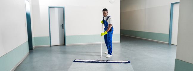 Male Janitor Cleaning Floor In Office