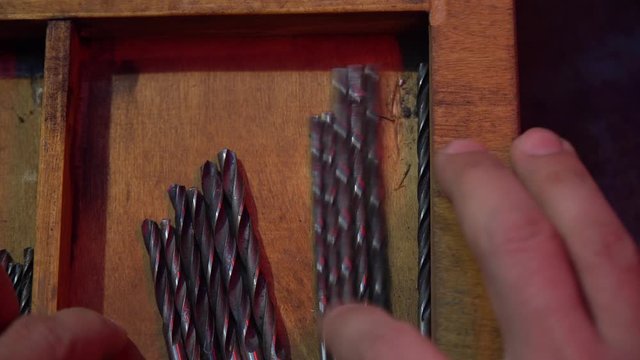 The man chooses the necessary drill among many others