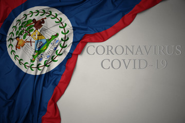 waving national flag of belize on a gray background with text coronavirus covid-19 . concept.