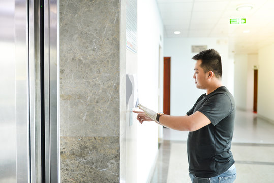 Asian man wearing medical glove press the elevator at office. Wuhan China coronavirus (COVID-19) outbreak prevention. Health care and medical concept. Protection against virus, infection, exhaust.