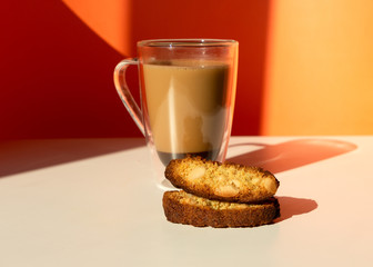 Biscotti almond cookies and a cup of coffee on the table on orange background. Geometric minimalist composition with shadow.