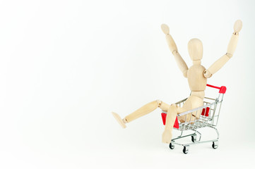 wooden mannequin in a shopping cart, shopping concept at sales