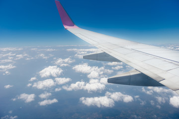 View from the airplane window on clouds, blue clear sky. Look seen through window of an aircraft. Good sunny cloudy weather