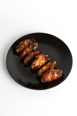 barbecue chicken wings close up on wooden tray shot with selective focus In the black plate, white background