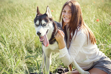 Beautiful woman playing with husky dog outdoors at park.