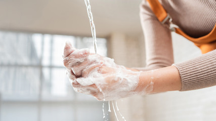 Asian woman use soap to wash your hands in the bathroom to get rid of the virus.
