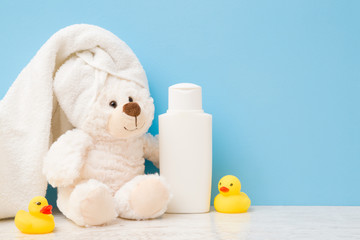 Smiling, lovely white teddy bear sitting with towel on head. Yellow rubber ducks and shampoo bottle...
