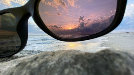 Sunset through pink tinted sun glasses on the beach during sunset
