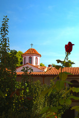Greek church tower with rose in front in bokeh - Vacation in Greece concept