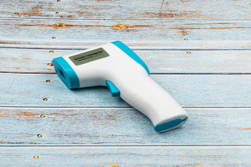 Non-contact infrared thermometer isolated on wooden background to measure a body temperature.