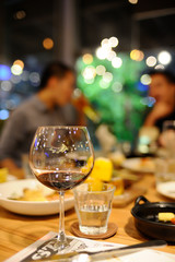 Glass of wine and a glass of water were put on the table in a restaurant, blurred background is a group of friends meet. with beautiful bokeh.