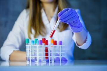 A medical professional, laboratory assistant, doctor performs an analysis in a laboratory, uses test tubes, a pipette and a petri dish for the presence of bacteria in the human body