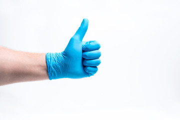 A man's hand in a blue rubber glove with a finger raised. The concept of success, approval.