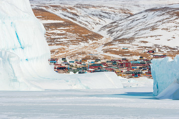 Village of Qaanaaq behind icebergs, Greenland. © Mikael