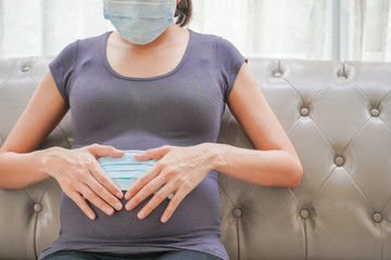 A pregnant woman wears a surgical mask to protect a COVID-19 (Coronavirus) and PM 2.5 and show a...