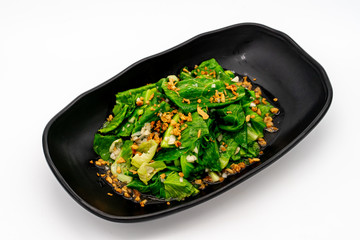 Fried Chinese Kale with chicken in black dish on white background.