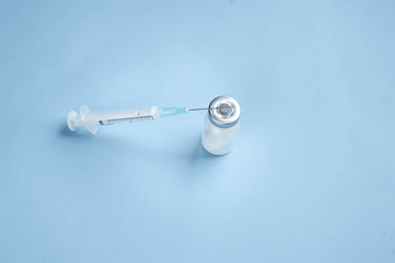 syringe and ampoule on a blue background.COVID-2019