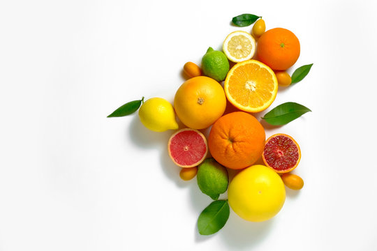 Close up image of juicy organic whole and halved assorted citrus fruits, green leaves & visible core texture, isolated white background, copy space. Vitamin C loaded food concept. Top view, flat lay. © Evrymmnt