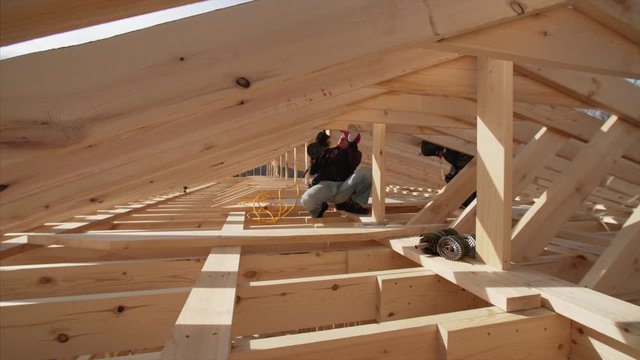 Timelapse of builders nailing wooden planks on the roof with pneumatic nail guns. Frame house under construction