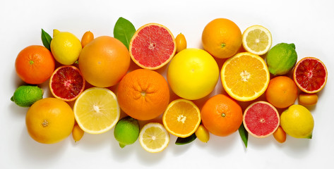 Close up image of juicy organic whole and halved assorted citrus fruits, green leaves & visible...
