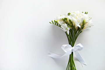 Delicate freesia bouquet on white background as spring holiday season symbol concept. Close up shot of fresh flowers with a lot of copy space for text. Minimalistic background.