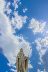 Virgin Mary statue with beautiful sky with clouds in background.