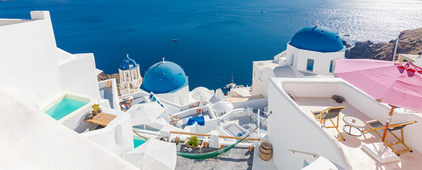 Amazing summer landscape, luxury vacation. Oia town on Santorini island, Greece. Traditional and famous houses and churches with blue domes over the Caldera, Aegean sea