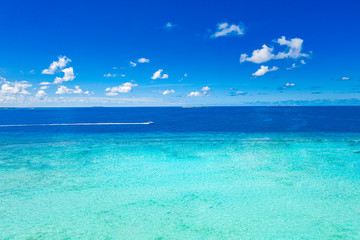 Amazing sea view and shades of blue and turquoise water at sunny day. Seascape with motorboat in bay. Summer ocean water