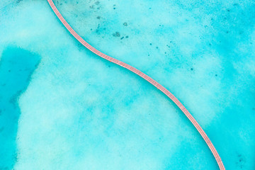 Beautiful aerial view of Maldives turquoise lagoon, top view with wooden jetty and crystal clear water