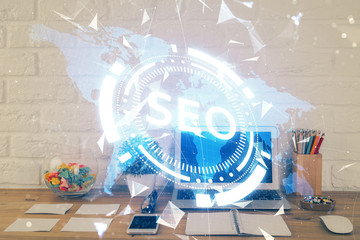 Double exposure of table with computer and seo drawing hologram. Search optimization concept.