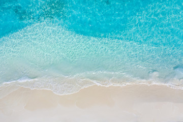 Obraz na płótnie Canvas Summer seascape beautiful waves, blue sea water in sunny day. Top view from drone. Sea aerial view, amazing tropical nature background. Beautiful bright sea with waves splashing and beach sand concept