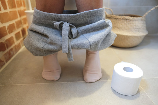 Frau sitzt auf wc mit Toilettenpapier