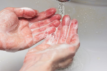 A woman washes her hands with soap.