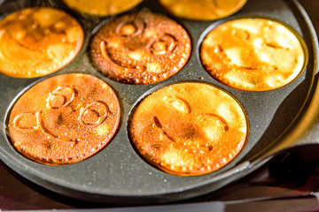 Fototapeta na wymiar pancake frying pan with smile face pancake cooking on cooker in kitchen