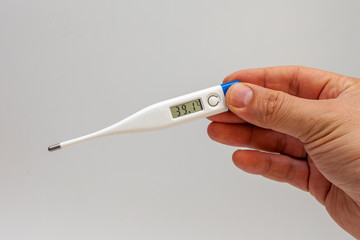 Man`s hands holding white electronic thermometer indicating high temperature. Virus alert.