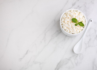 Cottage cheese in a white ceramic form on a marble background, top view, copy space.
