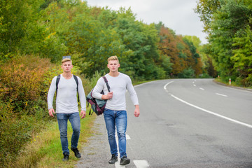 Company friends travelers hitchhiking at road nature background. Go near edge of city. Travellers on their way. Friends hitchhikers travelling. Begin great adventure in your life with hitchhiking