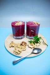 cranberry smoothie on a blue background with slices of nuts