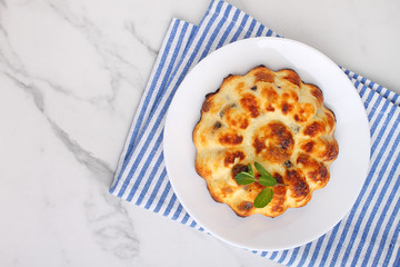 Cottage cheese casserole decorated with mint on a marble background, top view