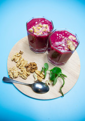 cranberry smoothie on a blue background with slices of nuts