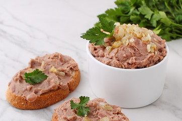 Bean paste with fried onions in a white ceramic form on a marble background.