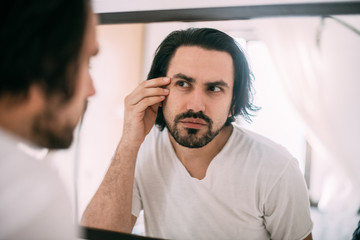 A handsome man looks in the mirror. Men's personal care