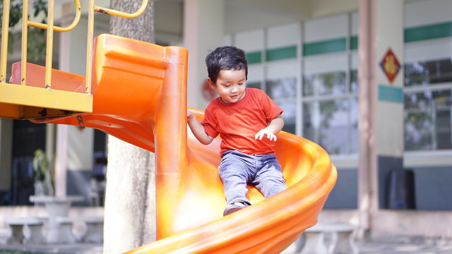 Cute little Asian 2 year old toddler baby boy child playing on a slide at indoor playground in department store, Baby Sliding Down Slide, Kid first experience concept.