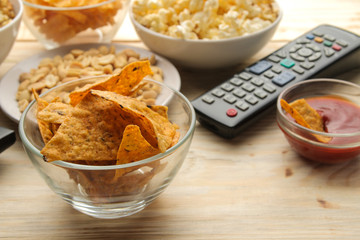 Popcorn, various snacks and tv remote on a natural wooden table. Concept of watching a movie or video at home.